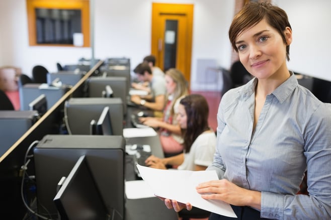 Teacher standing at the computer room holding papers in college.jpeg